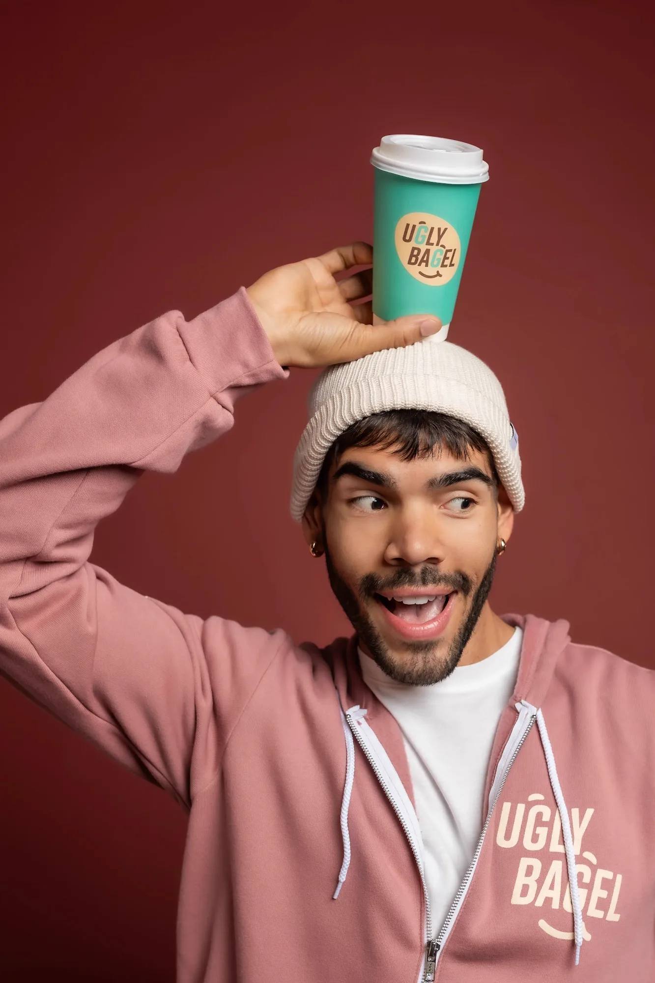 Child with Ugly Bagel products on a pink backdrop