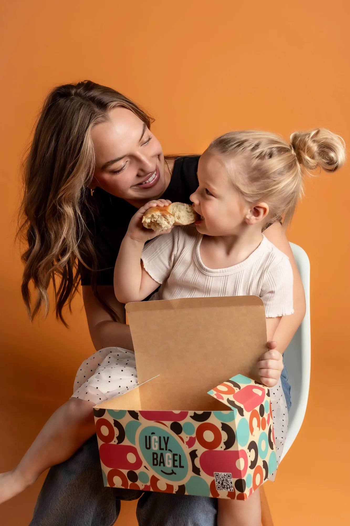 Child with an Ugly Bagel lunchbox on an orange backdrop