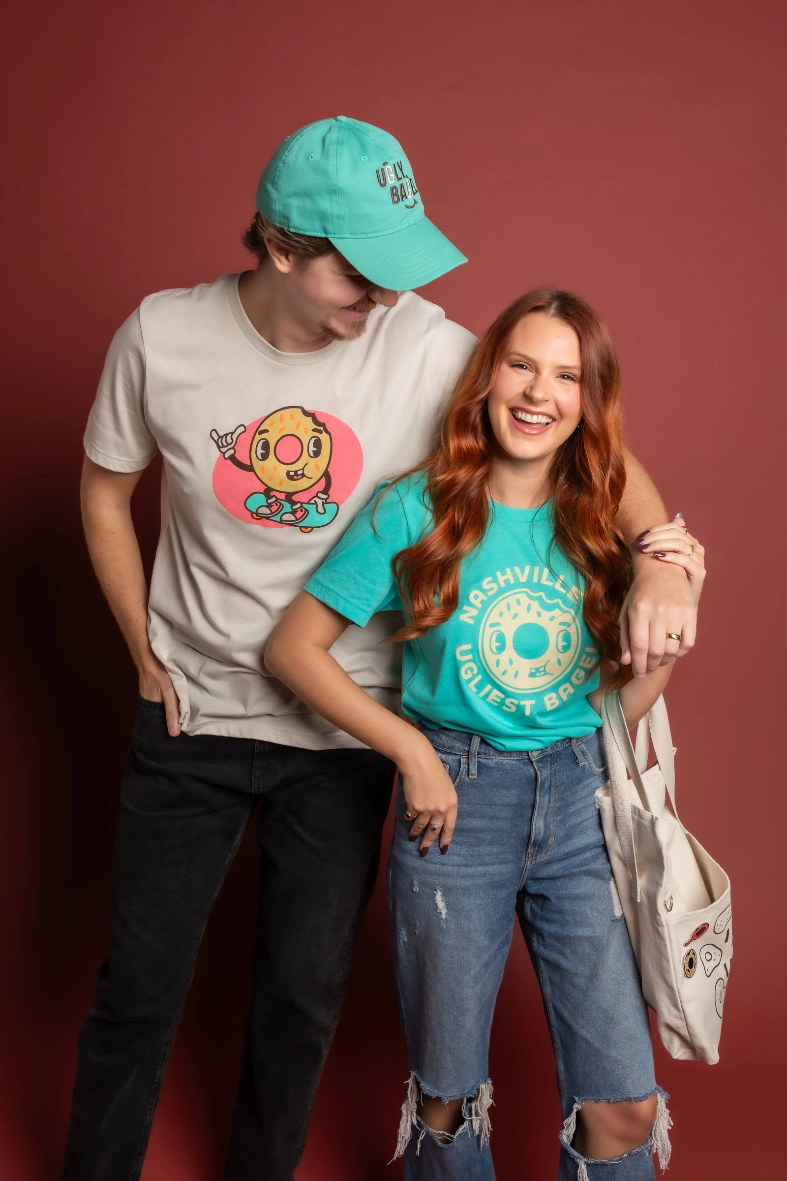 Couple wearing Ugly Bagel apparel against a pink backdrop