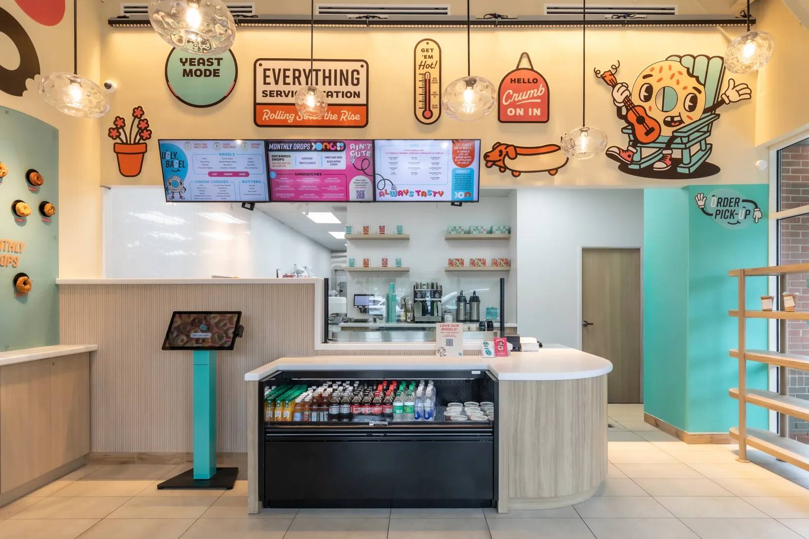 Wide view of the Ugly Bagel counter and digital menu boards