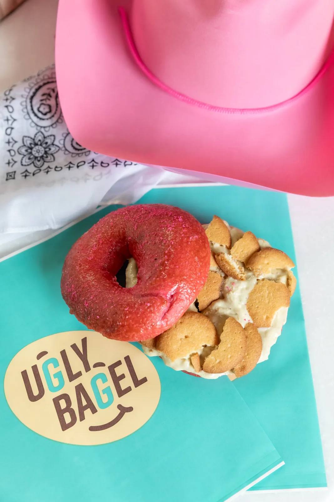 Ugly Bagel red bagel sandwich and chips on an Aqua bag